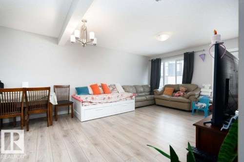 Living room featuring beamed ceiling, light wood-type flooring, and hanging lights - 96 1530 Tamarack Boulevard, Edmonton, AB - Indoor Photo Showing Living Room