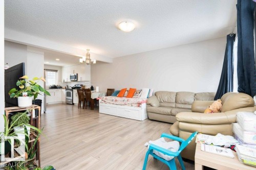 Living room with light wood-type flooring, a textured ceiling, and a chandelier - 96 1530 Tamarack Boulevard, Edmonton, AB - Indoor Photo Showing Living Room