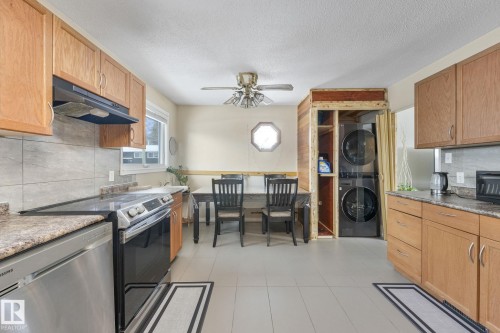 Kitchen with tasteful backsplash, stainless steel appliances, stacked washer and clothes dryer, a ceiling fan, and a textured ceiling - 2 Scarboro Place, St. Albert, AB - Indoor Photo Showing Kitchen