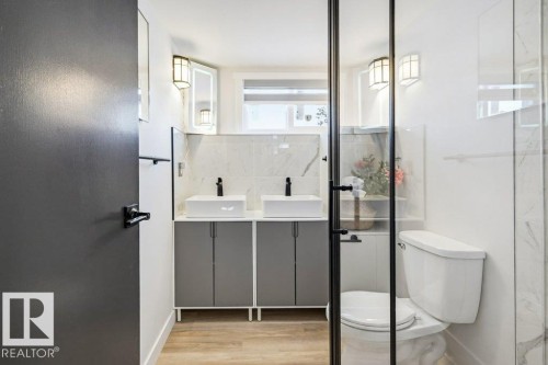 Full bathroom featuring double vanity, a shower stall, light wood finished floors, and backsplash - 7016 92A Avenue, Edmonton, AB - Indoor Photo Showing Bathroom