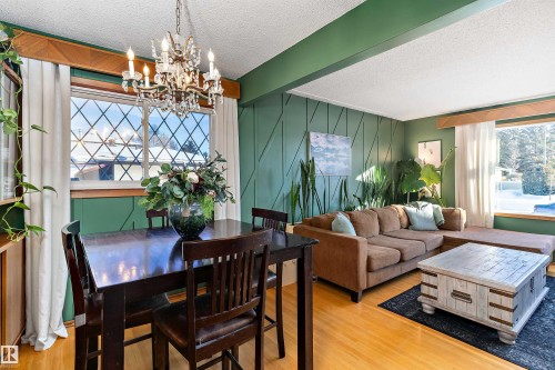 Dining area featuring a textured ceiling, light wood-type flooring, suspended lighting, and an accent wall - 7316 100 Avenue, Edmonton, AB - Indoor