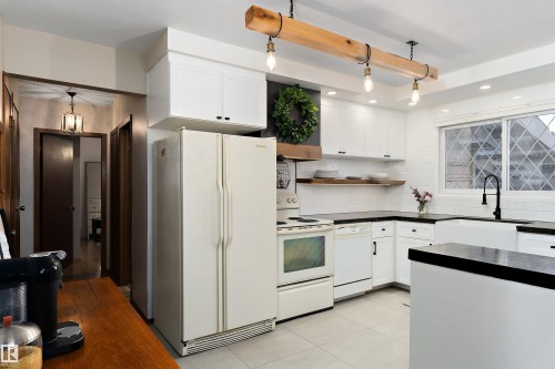 Kitchen with white appliances, white cabinetry, dark countertops, and pendant lighting - 7316 100 Avenue, Edmonton, AB - Indoor Photo Showing Kitchen