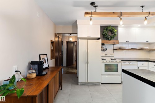 Kitchen featuring white appliances, white cabinetry, backsplash, dark countertops, and open shelves - 7316 100 Avenue, Edmonton, AB - Indoor Photo Showing Kitchen