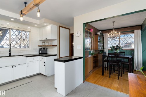 Kitchen featuring plenty of natural light, white cabinetry, light tile patterned flooring, and decorative backsplash - 7316 100 Avenue, Edmonton, AB - Indoor Photo Showing Other Room