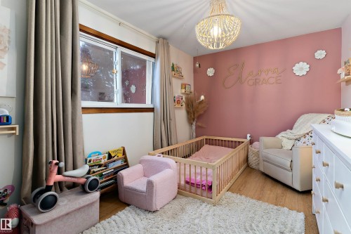 Bedroom with light wood-style floors, a nursery area, and suspended lighting - 7316 100 Avenue, Edmonton, AB - Indoor