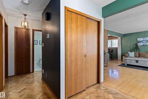 Hall featuring a textured ceiling, parquet flooring, and suspended lighting - 7316 100 Avenue, Edmonton, AB - Indoor