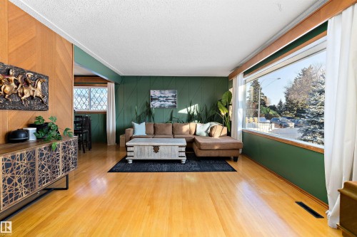 Living room with a textured ceiling, light wood-style flooring, and wood walls - 7316 100 Avenue, Edmonton, AB - Indoor