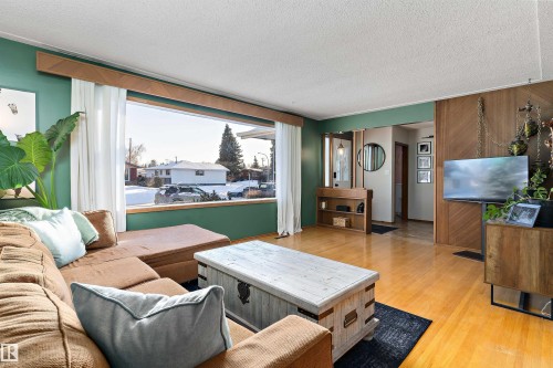 Living area with a textured ceiling, light wood finished floors, and ornamental molding - 7316 100 Avenue, Edmonton, AB - Indoor Photo Showing Living Room