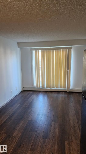 Unfurnished room with a textured ceiling, dark wood-style flooring, and a baseboard heating unit - 413 5521 7 Avenue, Edmonton, AB - Indoor Photo Showing Other Room