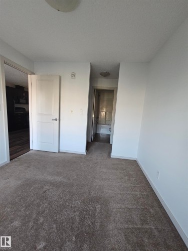 Unfurnished bedroom featuring dark carpet and a textured ceiling - 413 5521 7 Avenue, Edmonton, AB - Indoor Photo Showing Other Room