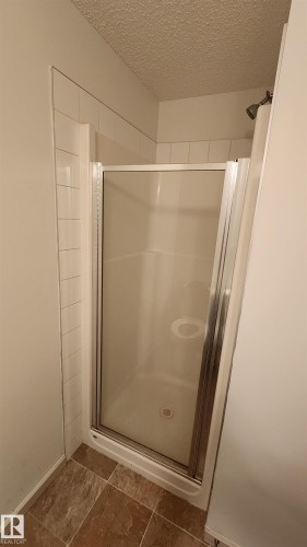 Full bathroom with a stall shower and a textured ceiling - 413 5521 7 Avenue, Edmonton, AB - Indoor Photo Showing Bathroom