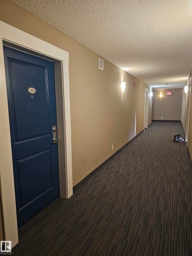 Corridor featuring a textured ceiling and dark colored carpet - 413 5521 7 Avenue, Edmonton, AB - Indoor Photo Showing Other Room
