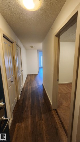 Hallway with a textured ceiling and dark wood finished floors - 413 5521 7 Avenue, Edmonton, AB - Indoor Photo Showing Other Room