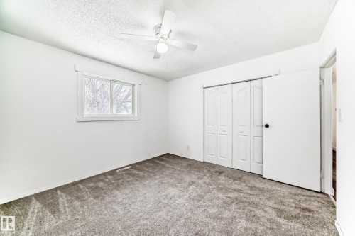 Unfurnished bedroom with carpet, a closet, a textured ceiling, and a ceiling fan - 13904 135 Avenue, Edmonton, AB - Indoor Photo Showing Other Room