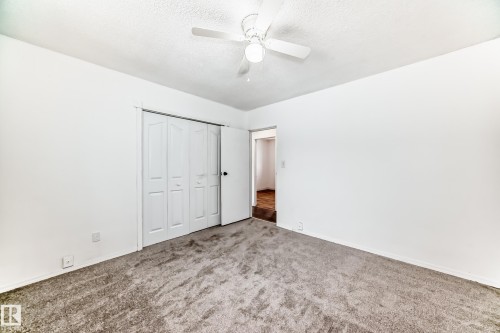 Unfurnished bedroom with carpet flooring, a closet, ceiling fan, and a textured ceiling - 13904 135 Avenue, Edmonton, AB - Indoor Photo Showing Other Room