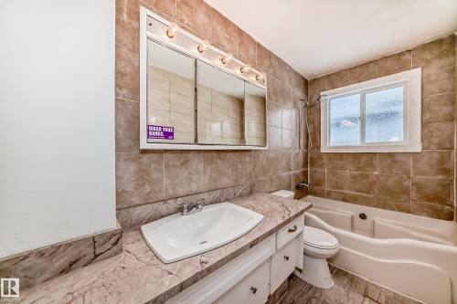 Bathroom with vanity, tile walls, shower / bathtub combination, and backsplash - 13904 135 Avenue, Edmonton, AB - Indoor Photo Showing Bathroom
