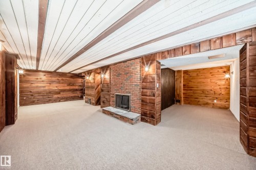 Finished below grade area featuring wood walls, a fireplace, light carpet, and wood ceiling - 13904 135 Avenue, Edmonton, AB - Indoor Photo Showing Other Room