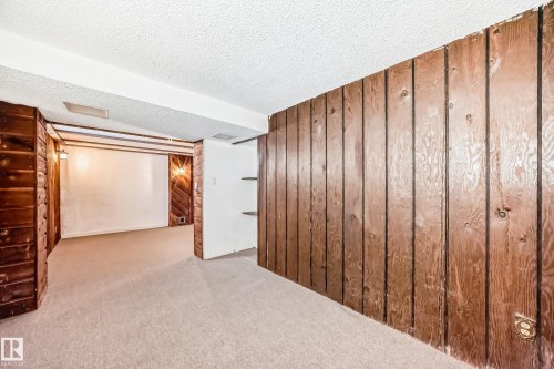 Finished basement with wooden walls, carpet, and a textured ceiling - 13904 135 Avenue, Edmonton, AB - Indoor Photo Showing Other Room