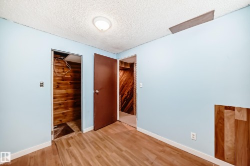 Unfurnished bedroom with a textured ceiling, a closet, and light wood-style floors - 13904 135 Avenue, Edmonton, AB - Indoor Photo Showing Other Room