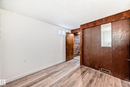 Unfurnished bedroom with a textured ceiling, light wood-style flooring, a closet, and wood walls - 13904 135 Avenue, Edmonton, AB - Indoor Photo Showing Other Room