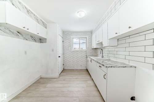 Kitchen with white cabinetry, light countertops, light wood finished floors, wallpapered walls, and backsplash - 13904 135 Avenue, Edmonton, AB - Indoor Photo Showing Kitchen