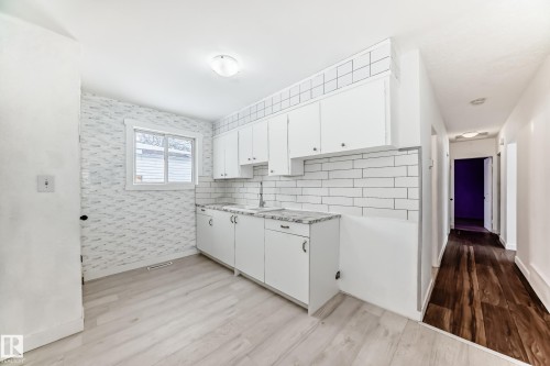 Kitchen featuring white cabinetry, light wood finished floors, light countertops, and decorative backsplash - 13904 135 Avenue, Edmonton, AB - Indoor Photo Showing Kitchen