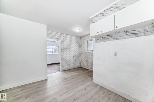 Spare room featuring light wood-style floors and brick wall - 13904 135 Avenue, Edmonton, AB - Indoor Photo Showing Other Room