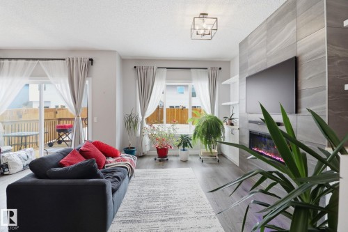 Living room with a fireplace, plenty of natural light, wood finished floors, and a textured ceiling - 3234 Chernowski Way, Edmonton, AB - Indoor Photo Showing Living Room With Fireplace