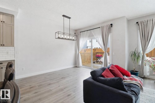 Laundry area featuring light wood-type flooring, a textured ceiling, and a chandelier - 3234 Chernowski Way, Edmonton, AB - Indoor