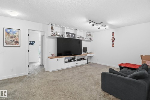 Living room with track lighting, a textured ceiling, and light colored carpet - 3234 Chernowski Way, Edmonton, AB - Indoor Photo Showing Living Room