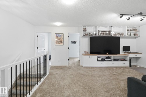 Living room featuring track lighting, light carpet, a textured ceiling, and an office area - 3234 Chernowski Way, Edmonton, AB - Indoor Photo Showing Other Room