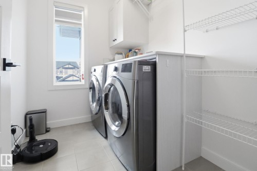 Laundry room featuring cabinet space, light tile patterned flooring, and washer and dryer - 3234 Chernowski Way, Edmonton, AB - Indoor Photo Showing Laundry Room