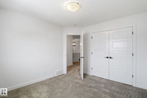 Unfurnished bedroom featuring carpet floors, a closet, and a textured ceiling - 3234 Chernowski Way, Edmonton, AB - Indoor Photo Showing Other Room