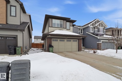 View of front of property featuring an attached garage and brick siding - 3234 Chernowski Way, Edmonton, AB - Outdoor