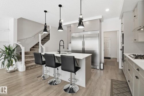 Kitchen with light wood-type flooring, stainless steel appliances, a center island with sink, hanging light fixtures, and a breakfast bar area - 3234 Chernowski Way, Edmonton, AB - Indoor Photo Showing Kitchen With Stainless Steel Kitchen With Upgraded Kitchen