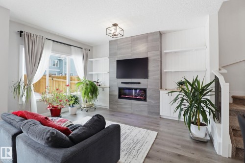 Living area with light wood-type flooring, built in features, a textured ceiling, and a tile fireplace - 3234 Chernowski Way, Edmonton, AB - Indoor Photo Showing Living Room With Fireplace