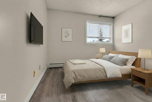 Bedroom with wood finished floors, a baseboard heating unit, and a textured ceiling - 25 11255 31 Avenue, Edmonton, AB - Indoor Photo Showing Bedroom
