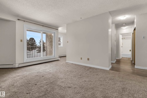 Unfurnished room with carpet flooring, a textured ceiling, and a baseboard radiator - 25 11255 31 Avenue, Edmonton, AB - Indoor Photo Showing Other Room