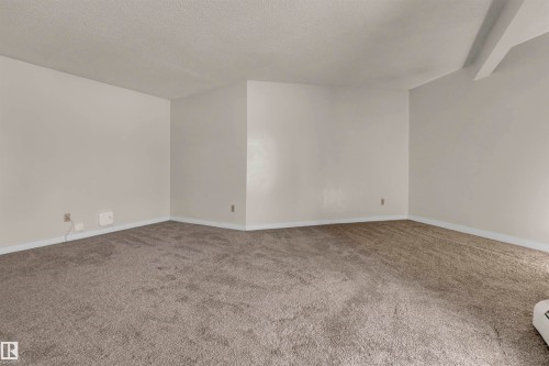 Carpeted spare room featuring a textured ceiling and baseboards - 25 11255 31 Avenue, Edmonton, AB - Indoor Photo Showing Other Room