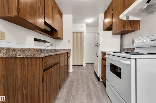 Kitchen featuring white electric range oven, exhaust hood, light wood finished floors, and wood finish cabinetry - 25 11255 31 Avenue, Edmonton, AB - Indoor Photo Showing Kitchen