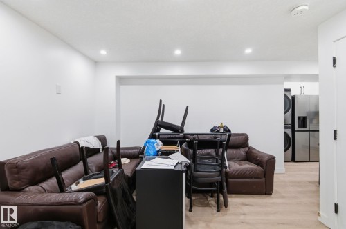 Living room featuring light wood-style floors, stacked washer and dryer, and recessed lighting - 13538 127 Street, Edmonton, AB - Indoor