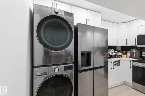 Laundry area with stacked washer and clothes dryer and light wood-type flooring - 13538 127 Street, Edmonton, AB - Indoor Photo Showing Laundry Room