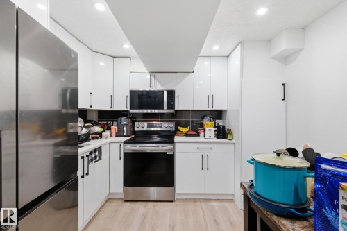 Kitchen with stainless steel appliances, white cabinetry, light wood finished floors, tasteful backsplash, and recessed lighting - 13538 127 Street, Edmonton, AB - Indoor Photo Showing Kitchen