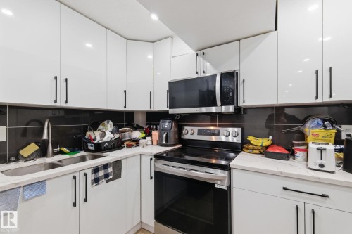 Kitchen with stainless steel appliances, white cabinetry, light stone countertops, decorative backsplash, and modern cabinets - 13538 127 Street, Edmonton, AB - Indoor Photo Showing Kitchen With Double Sink With Upgraded Kitchen