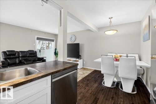 Kitchen with dark countertops, dishwasher, open floor plan, white cabinets, and beam ceiling - 47 230 Edwards Drive, Edmonton, AB - Indoor Photo Showing Other Room