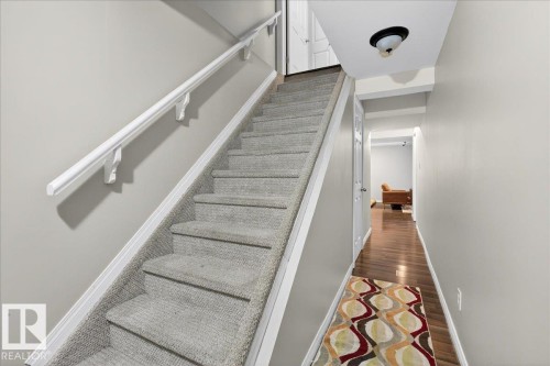 Stairs featuring baseboards and wood finished floors - 47 230 Edwards Drive, Edmonton, AB - Indoor Photo Showing Other Room
