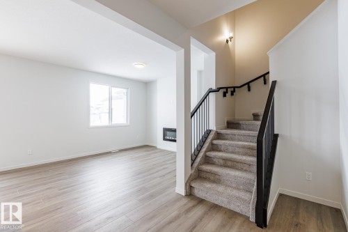 Stairs with wood finished floors, a glass covered fireplace, and heating unit - 75 Dansereau Way, Beaumont, AB - Indoor Photo Showing Other Room