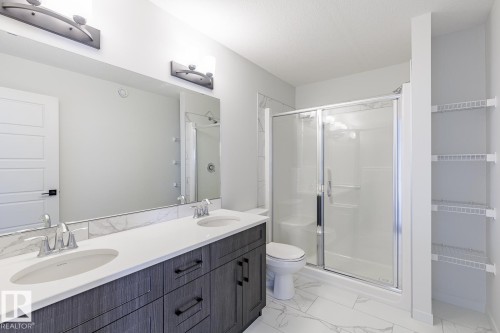 Full bathroom featuring double vanity, a shower stall, and light marble finish floors - 75 Dansereau Way, Beaumont, AB - Indoor Photo Showing Bathroom