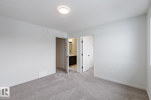 Unfurnished bedroom featuring a walk in closet, light colored carpet, and ensuite bathroom - 75 Dansereau Way, Beaumont, AB - Indoor