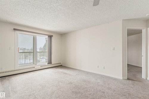 Carpeted spare room featuring baseboard heating, a textured ceiling, and ceiling fan - 312 11620 9A Avenue, Edmonton, AB - Indoor Photo Showing Other Room